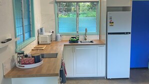 Eine kleine Küche mit Fenster, Deckenventilator und einem weißen Kühlschrank.