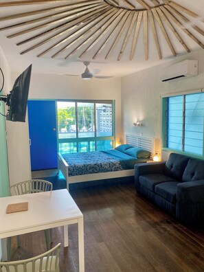 A room with a bed, a sofa, a table, and a ceiling fan.