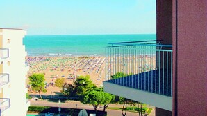A view of a beach with umbrellas and people from a balcony overlooking the sea. - Cozy studio with sea view in Lignano Sabbiadoro (Lignano Sabbiadoro)