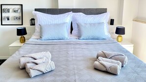 A neatly made bed with a patterned bedspread, two pillows, and two towels on the bed. - DRAMA @ Danza Del Mar / for Adults - View, Heated pool, Hot tub, Fast WI-FI (Vir)