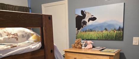 A bedroom with a bunk bed, a wooden dresser, a wall-mounted vent, and a landscape painting.