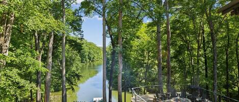 A lakeside deck with outdoor seating and a view of a river.