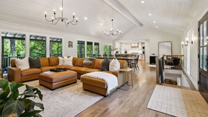 Amplia sala de estar con un sofá modular grande, un comedor y una cocina al fondo.