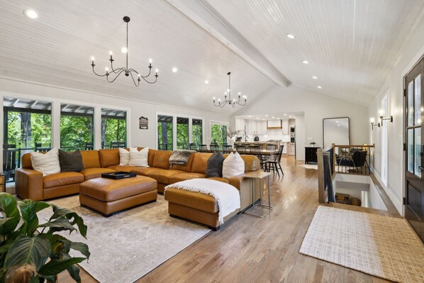 A spacious living room with a large sectional sofa, a dining area, and a kitchen in the background.
