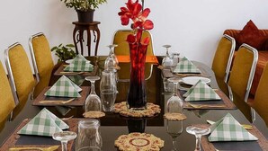 A formal dining table set with green and white checkered napkins, clear glassware, and a red orchid centerpiece. - Holiday Bungalow available for families and groups (10 people) (Kandy)