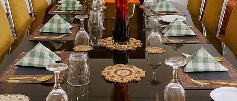 A formal dining table set with green and white checkered napkins, clear glassware, and a red orchid centerpiece.