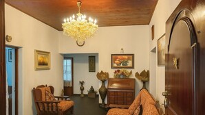 A room with a wooden ceiling, a chandelier, a sofa, a chair, a wooden cabinet, and a door. - Holiday Bungalow available for families and groups (10 people) (Kandy)