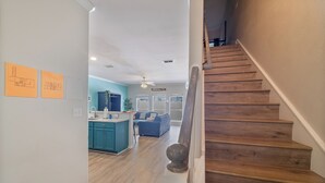 A staircase leading to a living area with a kitchen in the background.