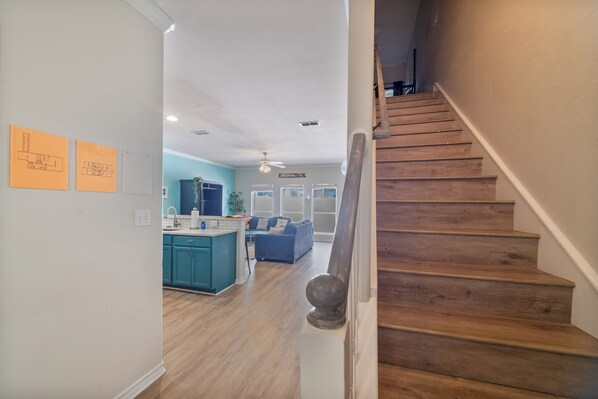 A staircase leading to a living area with a kitchen in the background. - Pet-Friendly Coastal Townhome | Heated Pool & Private Patio (Corpus Christi)