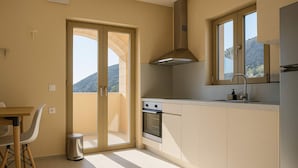 A modern kitchen with a sliding glass door leading to a balcony, a built-in oven, and a window with a mountain view.