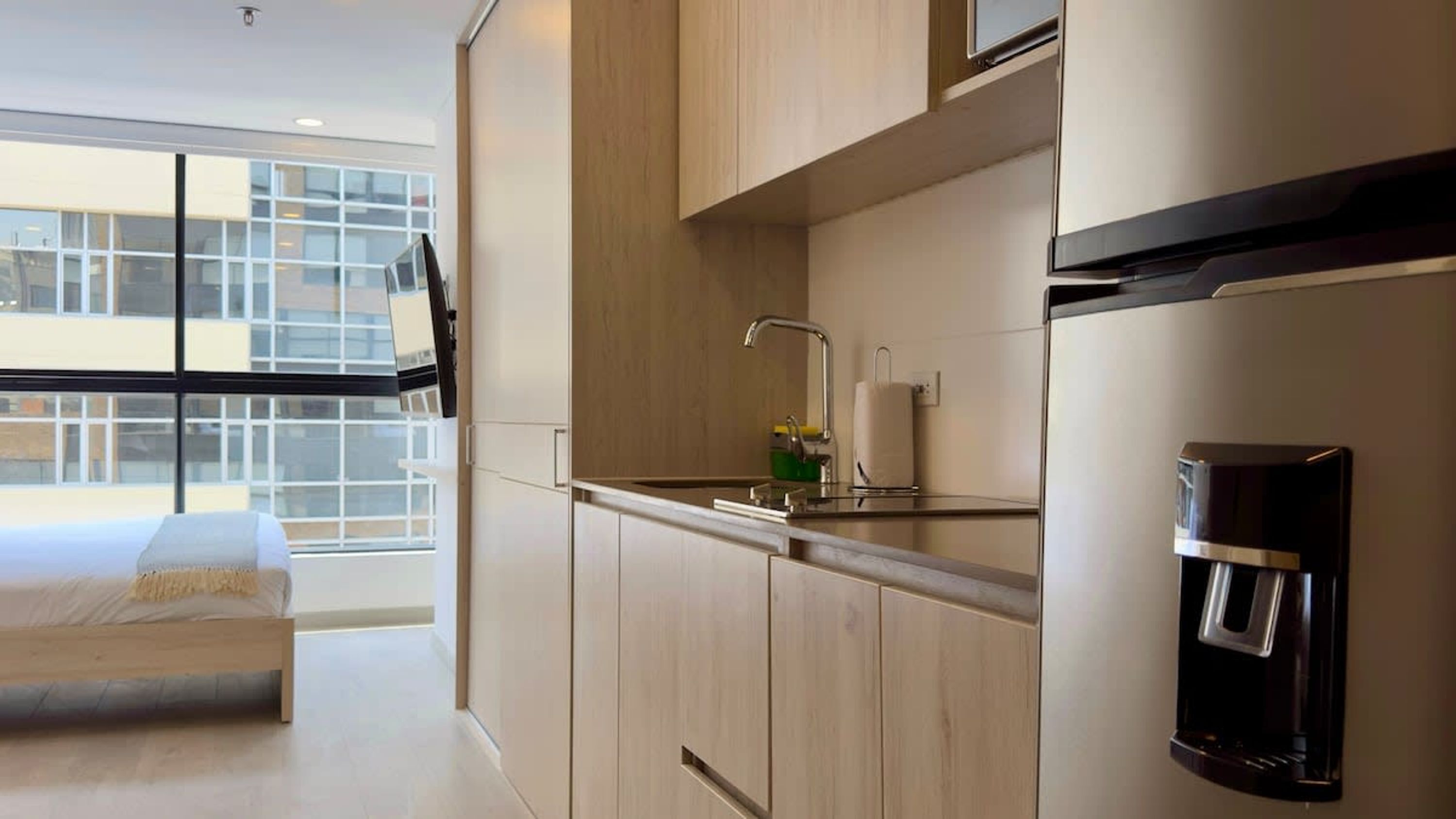 A modern kitchen with a built-in sink, a coffee machine, and a window overlooking the city.