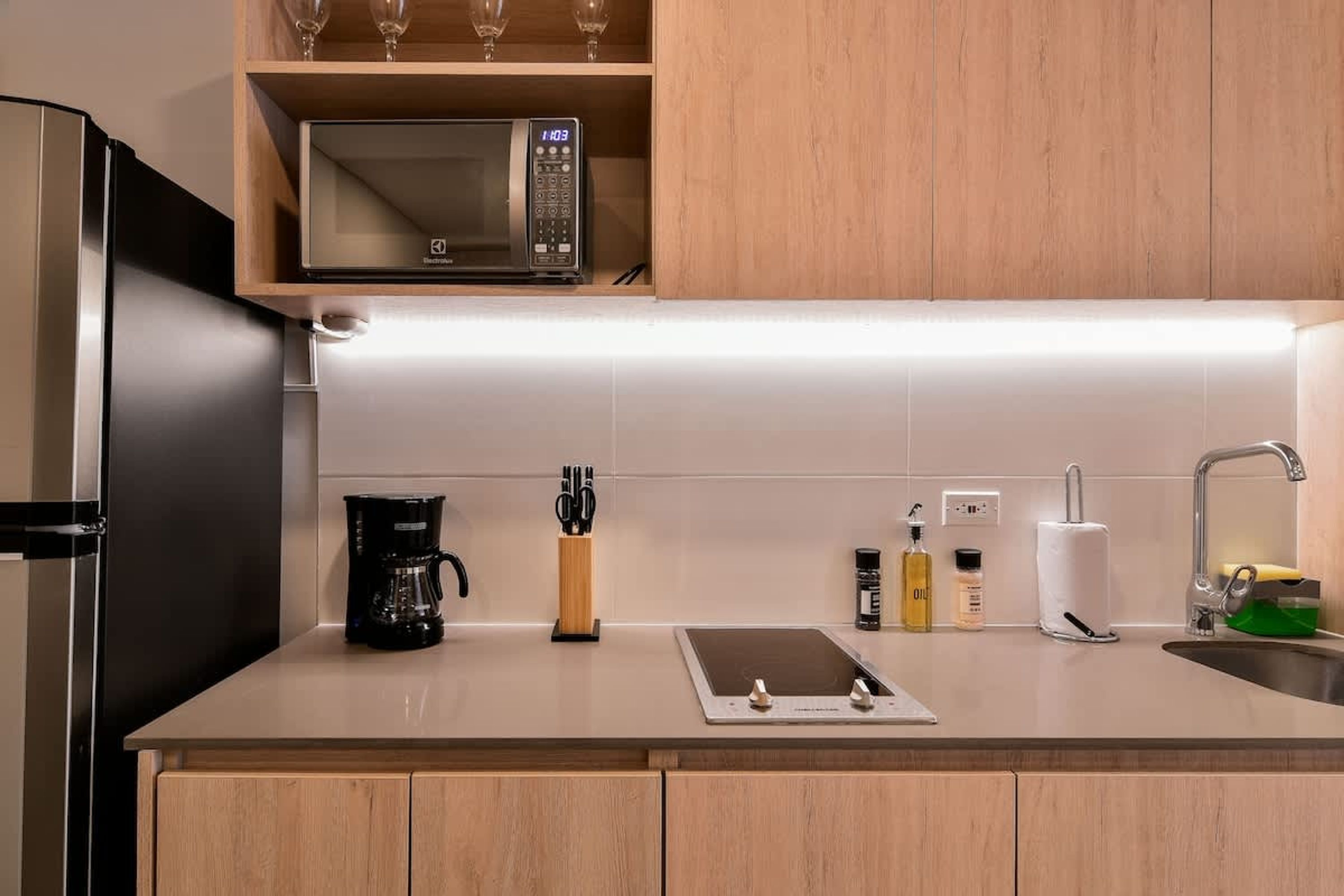 Una cocina moderna con microondas integrado, cafetera y refrigerador de acero inoxidable.