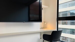 A modern room with a large flat-screen TV mounted on a white wall, a small desk with a lamp, and a black chair. - NOK Stylish Loft in Usaqu n (Bogotá)