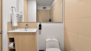 A modern bathroom with a white sink, mirror, and toilet, and beige tiled walls. - NOK Stylish Loft in Usaqu n (Bogotá)