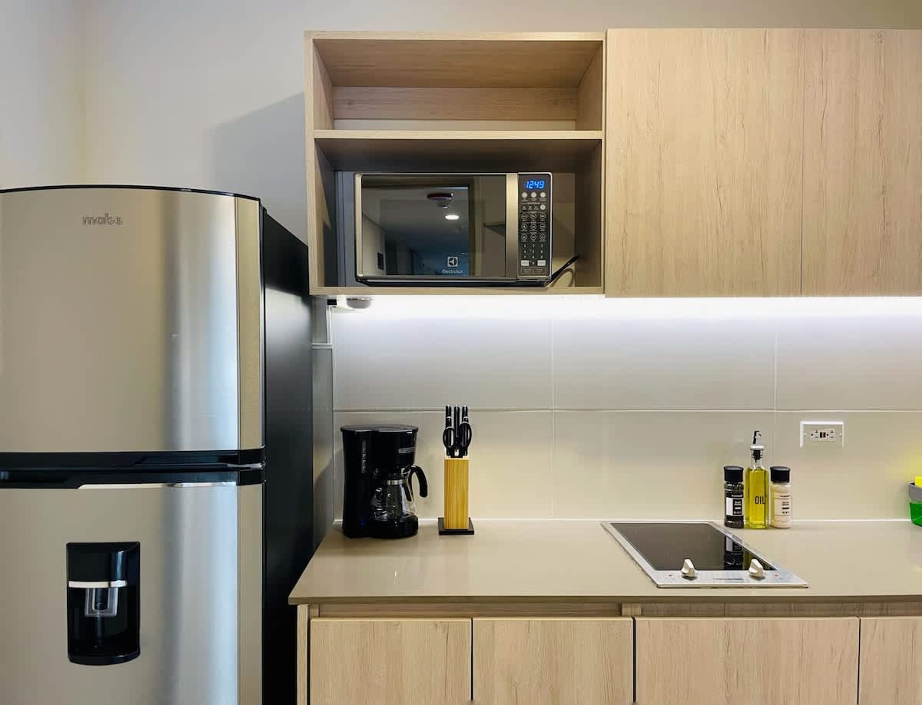 A modern kitchen with a stainless steel refrigerator, a microwave, a coffee maker, and a sink with a faucet.