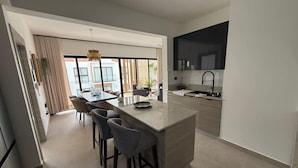 Une cuisine moderne dotée d’un îlot central, de tabourets de bar et d’un coin repas avec une table et des chaises.