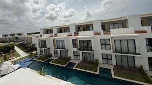 Un hôtel moderne composé de plusieurs bâtiments blancs, doté d’une piscine centrale et offrant une vue sur un ciel dégagé.