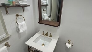 A bathroom with a white sink, a mirror, and a towel rack.