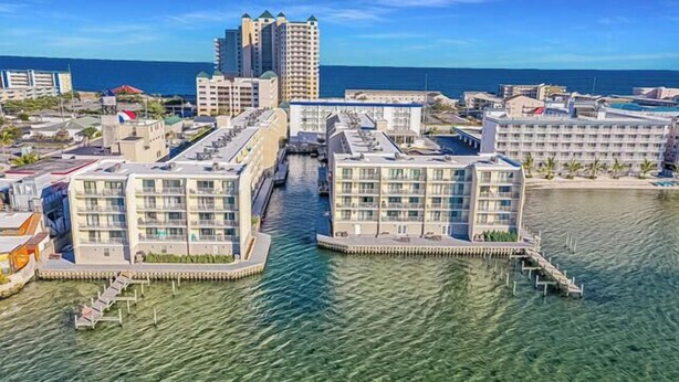 A waterfront hotel with multiple buildings, clear water, and a dock. - Canal front on one side, bay on the other! Perfect midtown 2 bedroom condo next to Seacrets and close to everything! Wight Bay #452 (Ocean City)