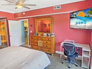 A bedroom with a bed, dresser, desk, chair, and a TV displaying 'OCMD GETAWAYS'. - Ocean block 3 Bedroom condo with rooftop pool just steps to the ocean! Ocean Palms #204 (Ocean City)