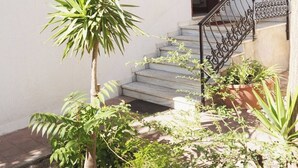 Ein weißes Gebäude mit zwei Rundbogenfenstern und einer Treppe mit schmiedeeisernem Geländer.