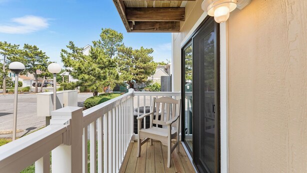 A wooden deck with a white railing, a chair, and a table.