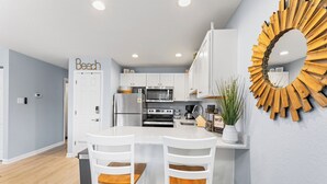 A modern kitchen with white cabinets, a central island, and a decorative sunburst mirror.