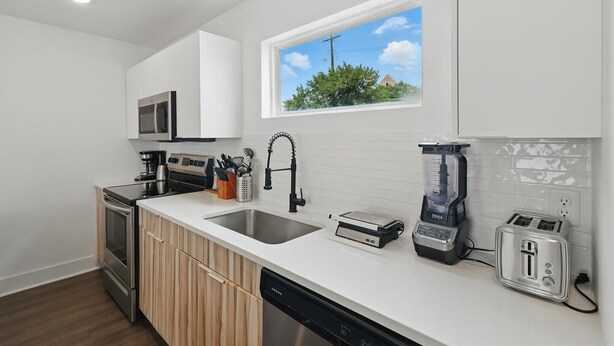 A modern kitchen with white cabinetry, a built-in microwave, a sink, a toaster, and a blender. - Heart of Dallas in Knox Henderson | Sleeps 4 (Dallas)