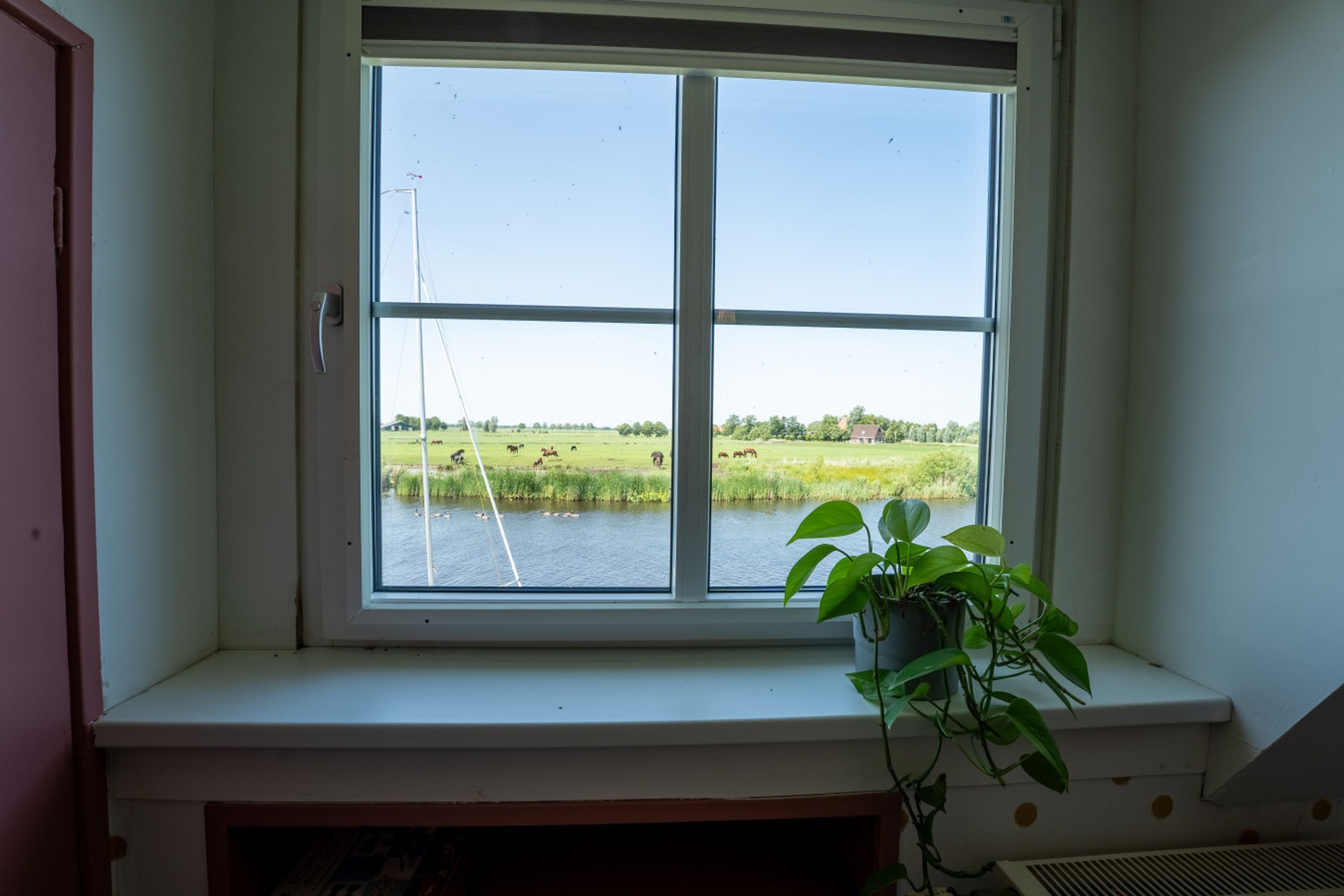 A room with a large window overlooking a river and a field.