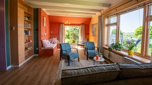 Un salon chaleureux avec un canapé, deux fauteuils, une table basse et une bibliothèque.