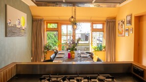 Un coin repas avec une table dressée pour quatre personnes, une cuisinière à gaz et une vue dégagée grâce à de grandes fenêtres.