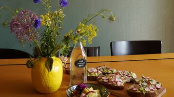 En matplats med ett bord dukat för en måltid, en vas med blommor och hängande lampor med växter.