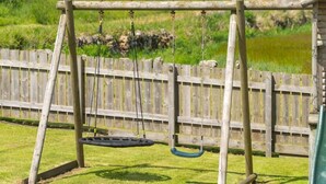 A wooden swing set in a grassy area with a wooden fence in the background. - Woodside Family Pet-friendly Holiday Home With Hot Tub (Fraserburgh)
