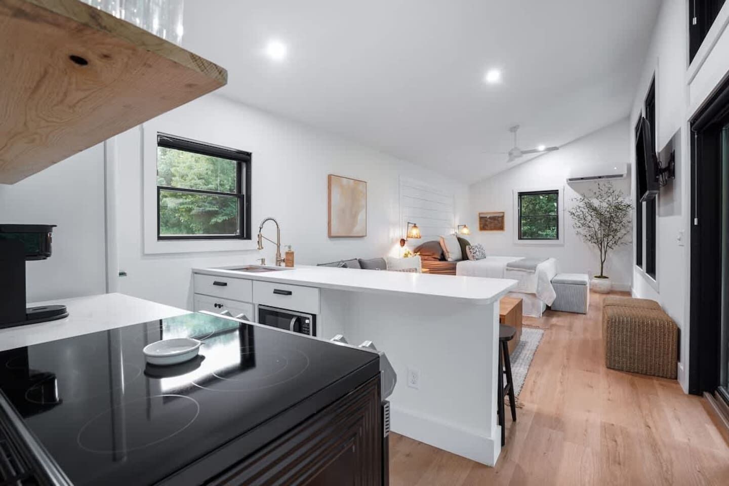 A modern kitchen with a central island, white cabinetry, and a dining area with a sofa and table.