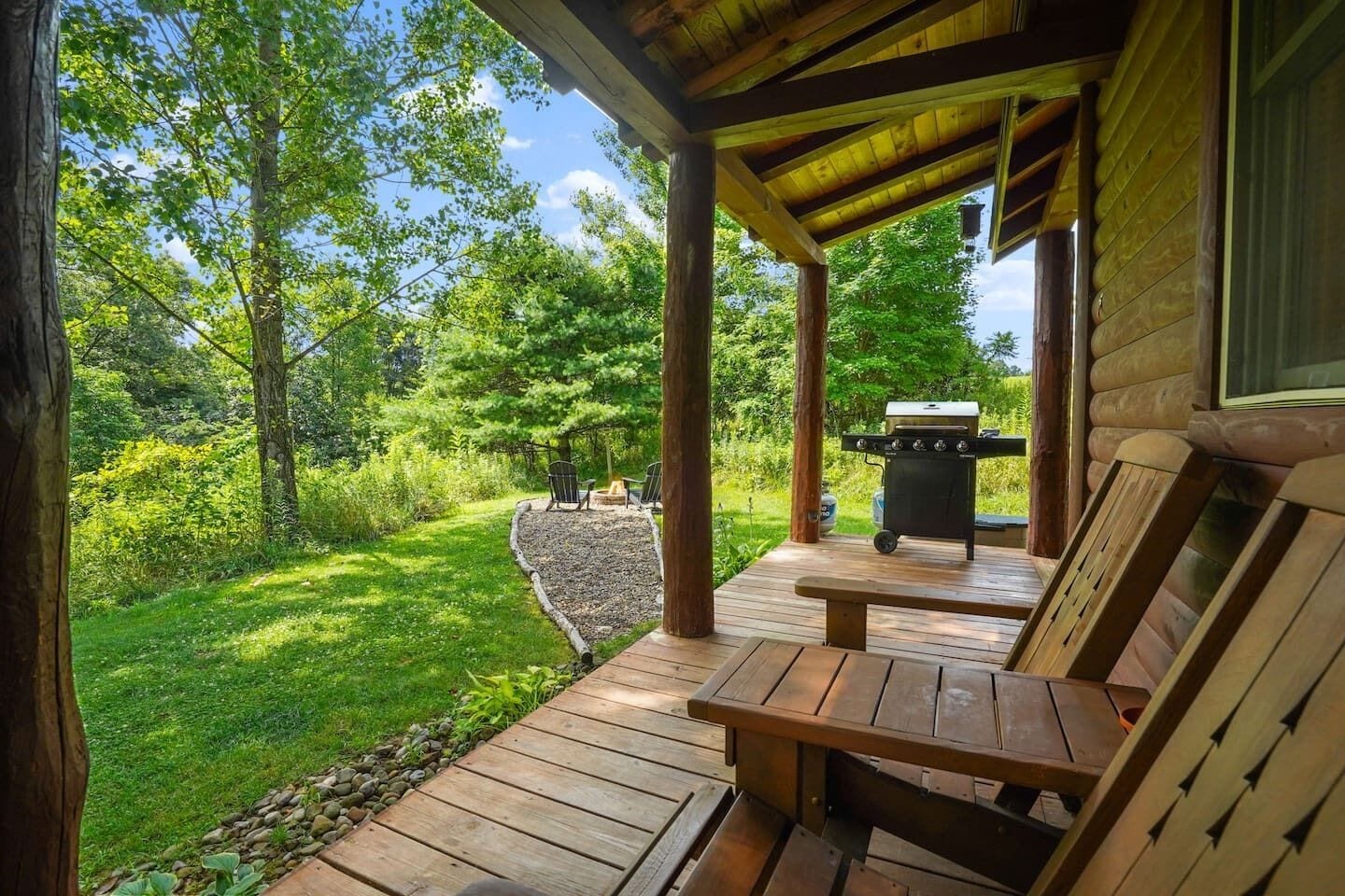 Eine Holzterrasse mit Sitzgelegenheiten und einem Grill.