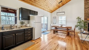 A modern kitchen with dark cabinets, a white refrigerator, and a wooden ceiling.