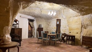 Un coin repas rustique avec un mur en pierre, des meubles en bois et un lustre.