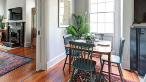 A dining area with a table set for four, a fireplace, and a large window. - The Murphy House Parlor Suite  | Chippewa View (Savannah)