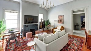 A living room with a fireplace, sofa, and a chandelier. - The Murphy House Parlor Suite  | Chippewa View (Savannah)