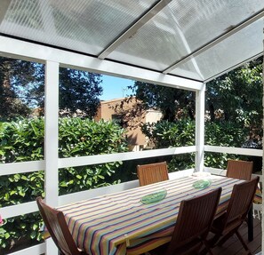 A covered patio with a table and chairs, surrounded by greenery and a view of buildings. - Bright, quiet, one-floor Villa of 95 m2 with Terrace, Nîmes – 4 pers. (Nîmes)