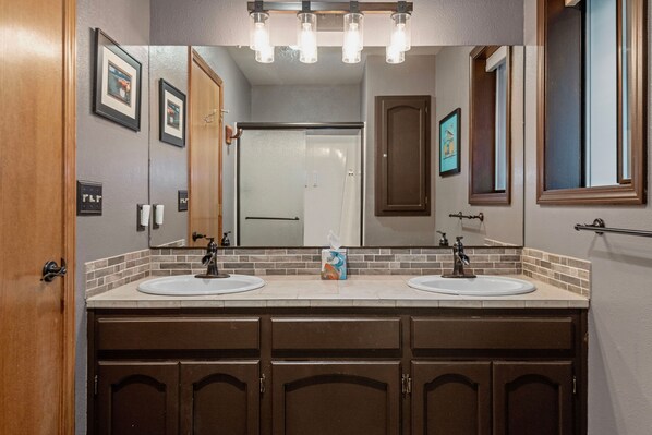 A bathroom with two sinks, a mirror, and a towel dispenser.