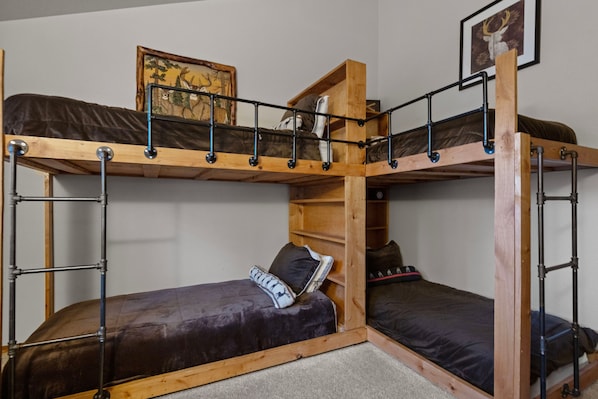 A bunk bed room with a wooden frame, metal railings, and a painting on the wall.