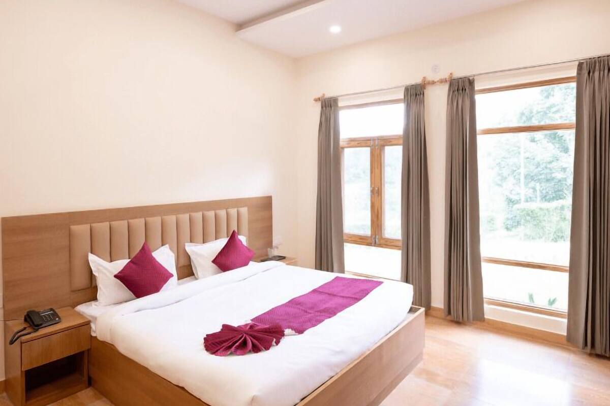 A hotel room with a large bed, wooden headboard, and a bedside table with a phone.