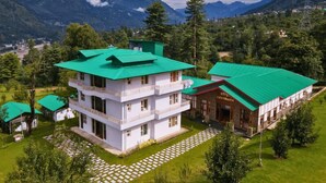 A multi-story building with a green roof, surrounded by lush greenery and mountains in the background. - RishiBhumi Wellness Retreat - Manali (Kullu)