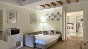 A bedroom with a bed, bedside tables, a lamp, a bookshelf, and a wall with decorative plates. - 1-bed Flat Near The Duomo (Milan)