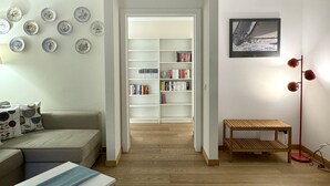 A living room with a sofa, a coffee table, a bookshelf, and a floor lamp. - 1-bed Flat Near The Duomo (Milan)