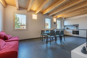 Un interior moderno con comedor, cocina y un sofá rojo.