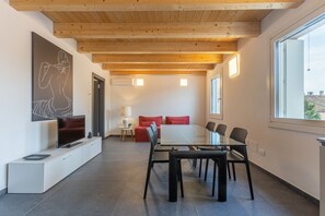 A modern interior with a dining area, a TV, and artwork on the wall. - GuestHost - New and spacious apartment of about 145 sqm, capable of accommodating up to 11 people, located on the second floor of a modern building without a lift.The property is located in a residential area of ​​Ferrara, a few minutes walk from the (Ferrara)