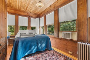A bedroom with a large bed, a wooden ceiling, and a view of greenery outside. - Tidebend: River Views and Gracious Comfort (Gloucester)
