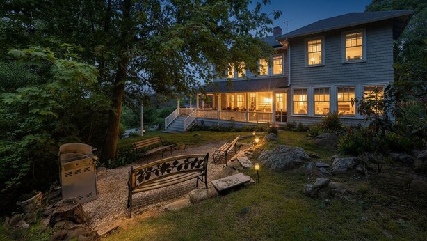 A two-story house with a covered porch, a grill, and a bench in the yard. - Tidebend: River Views and Gracious Comfort (Gloucester)